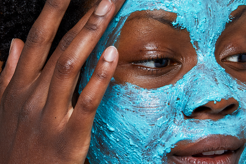 A close up on someone as they apply the bright blue Don’t Look At Me Fresh Face Mask over their entire face.