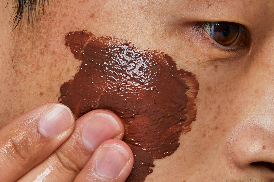 A close up on someone’s face as they apply Glen Cocoa Fresh Face Mask to their cheek.