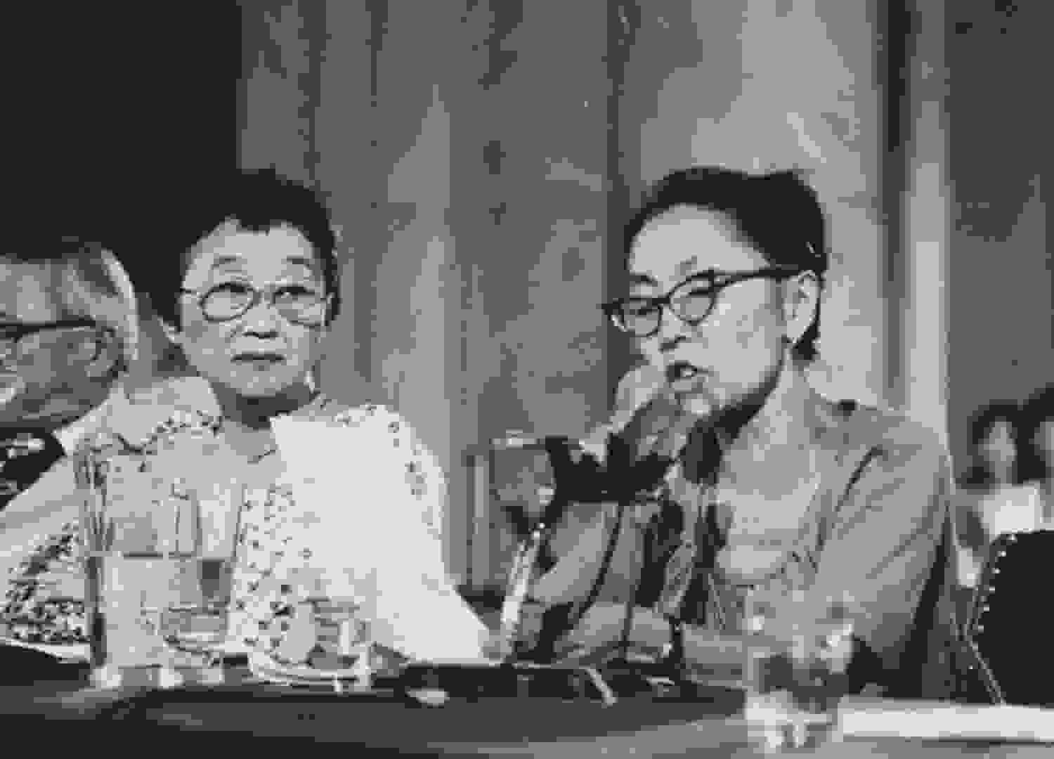 A black and white photo of a Japanese woman reading a speech